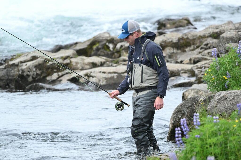 A man in a waders and hat is fishing