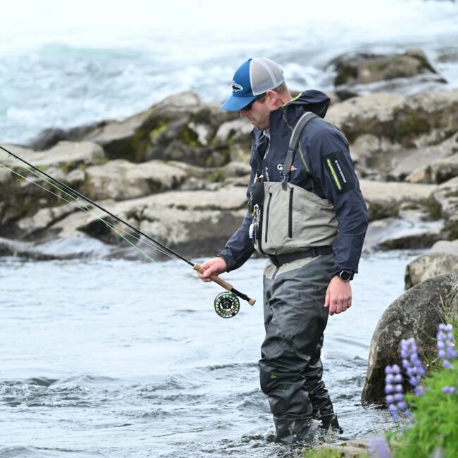 A man in a waders and hat is fishing